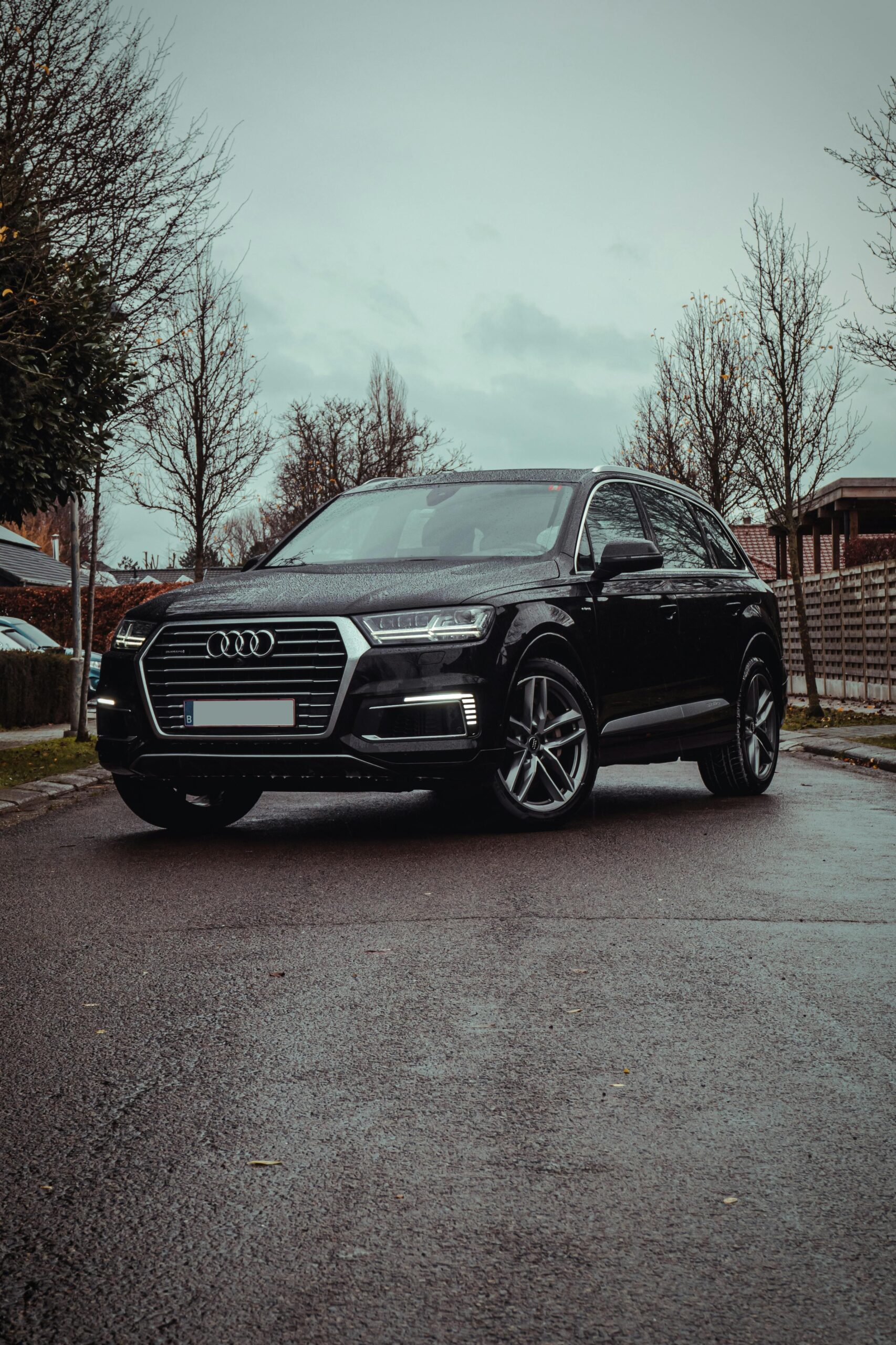Elegant black luxury car parked on a rainy street, showcasing modern design and style.